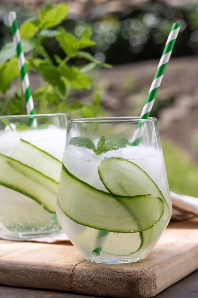 Glass of cucumber collins cocktail with cucumber slices.