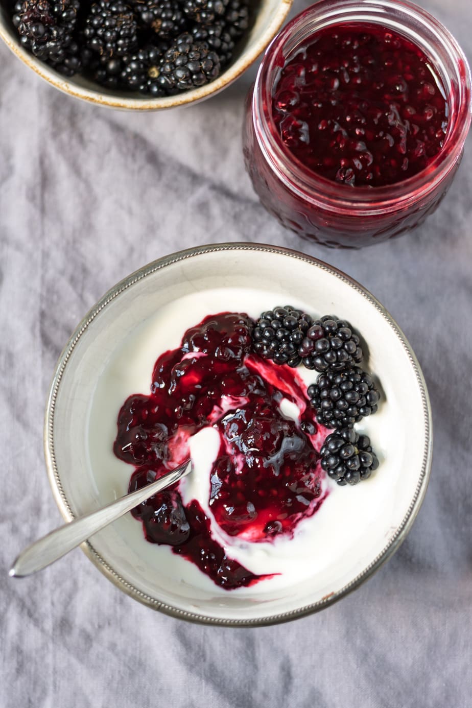 Bowl of yogurt topped with compote and blackberries.