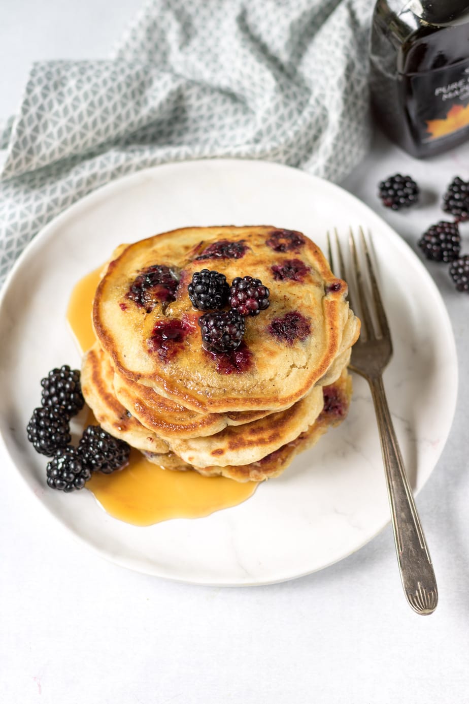 Stack of blackberry pancakes with syrup.