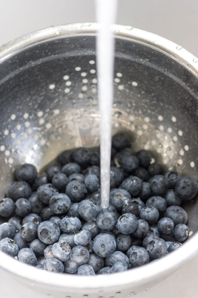 Washing blueberries in a colander.