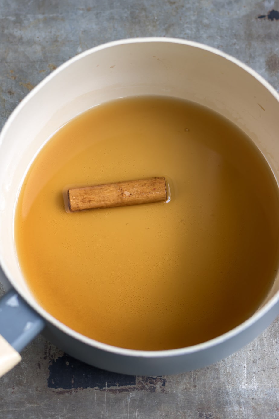 Cinnamon stick in sugar syrup in a pot.