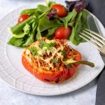 Vegan stuffed pepper on a plate with salad.