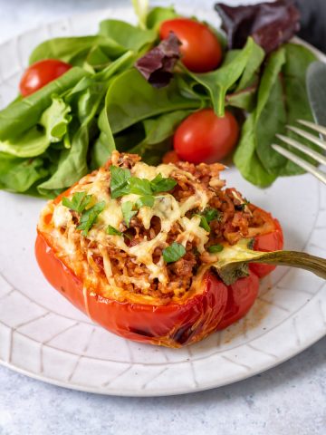Vegan stuffed pepper on a plate with salad.