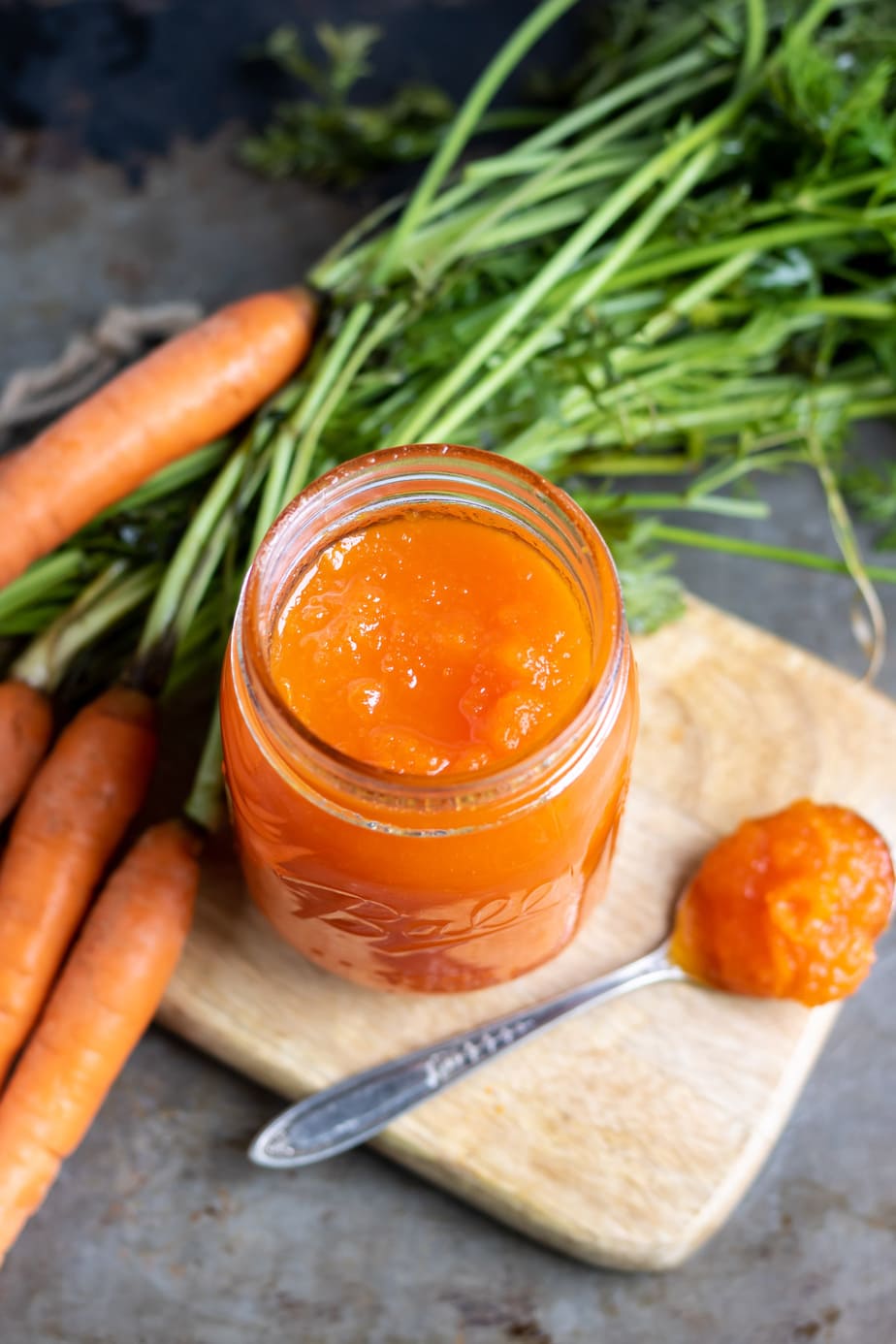 Looking down at a jar of jam with carrots and a spoonful next to it.