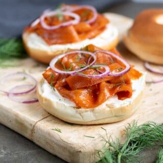 A bagel with carrot lox, cream cheese, onion and dill.