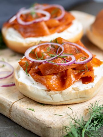 A bagel with carrot lox, cream cheese, onion and dill.