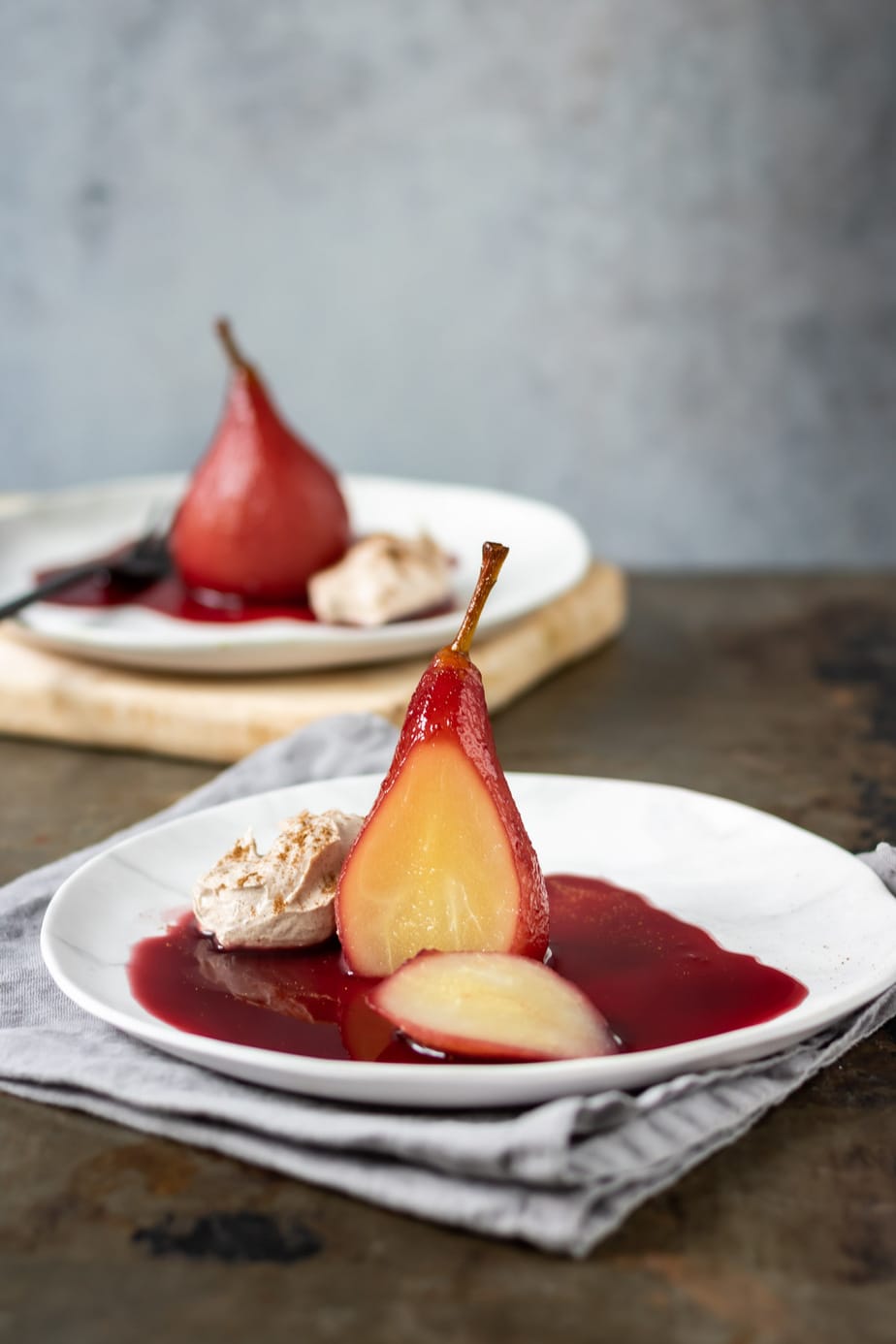Poached pear on a plate with a slice cut out.