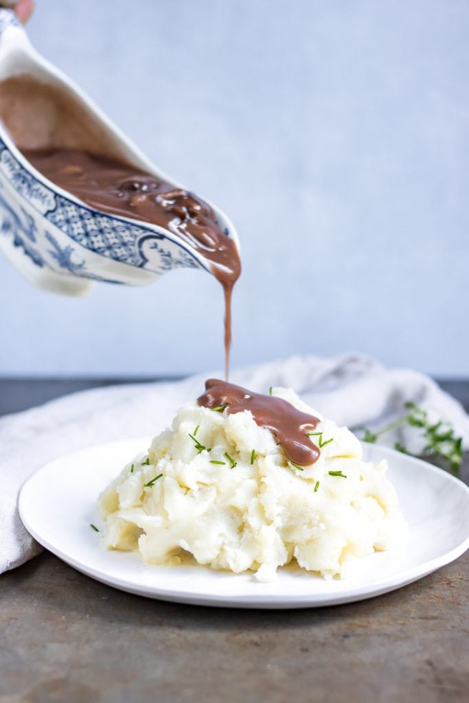 Pouring gravy on mashed potatoes.