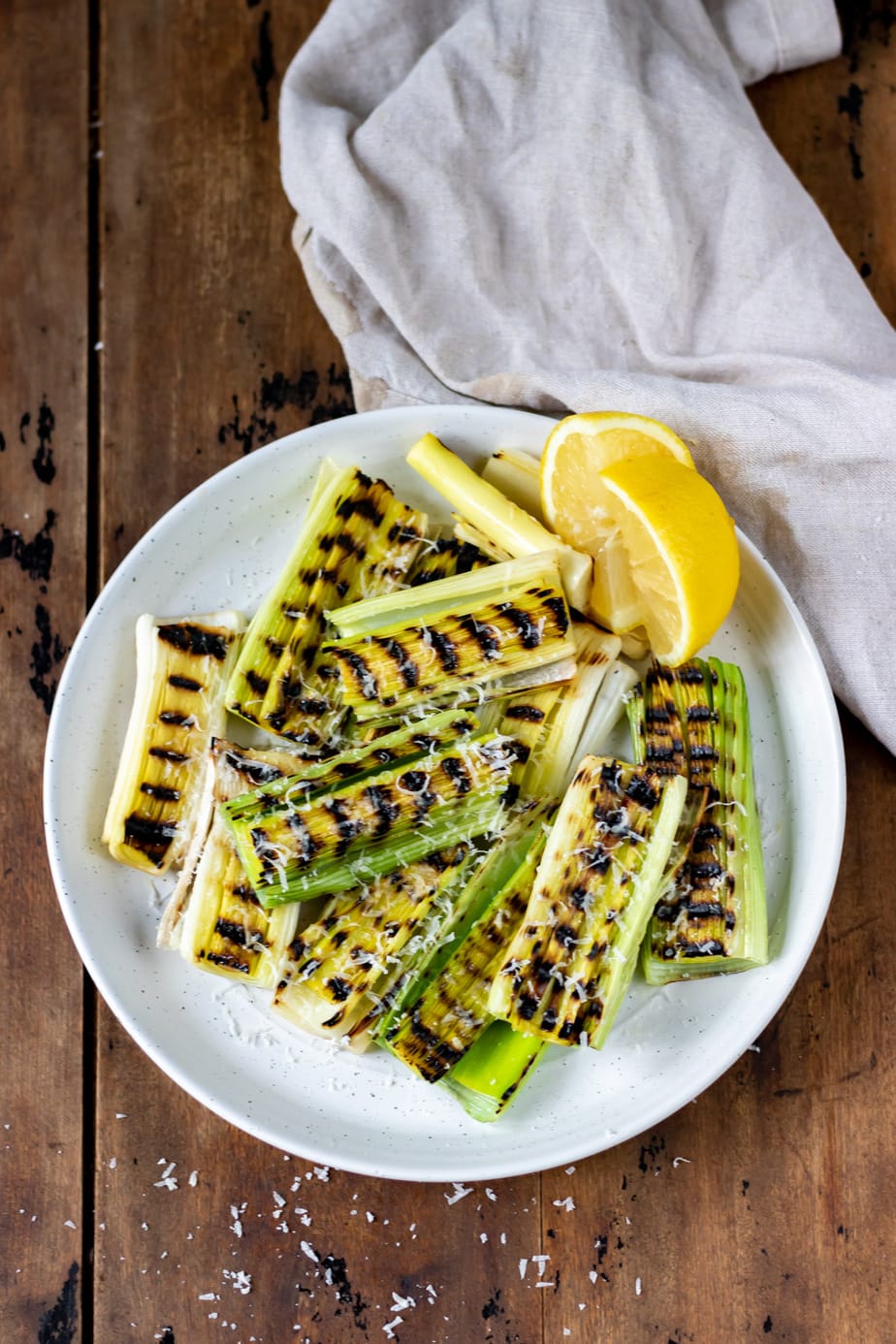 Plate of grilled leeks with a wedge of lemon.