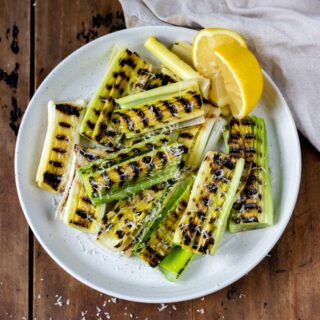 Plate of grilled leeks with a wedge of lemon.