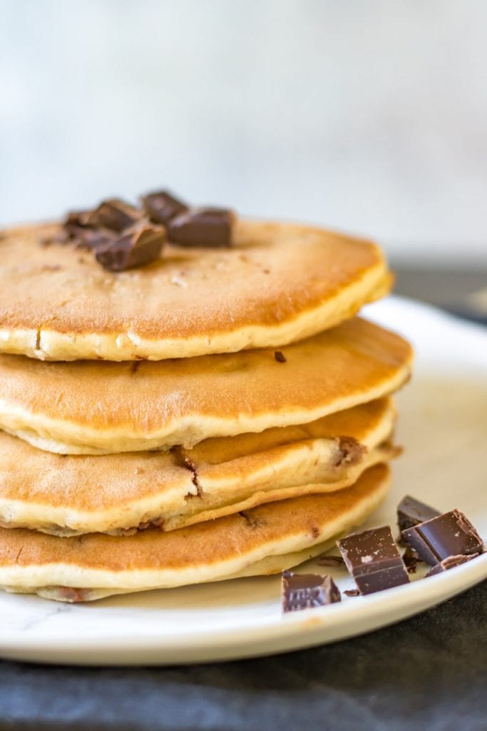 Close up of a stack of pancakes with chocolate chips on top.