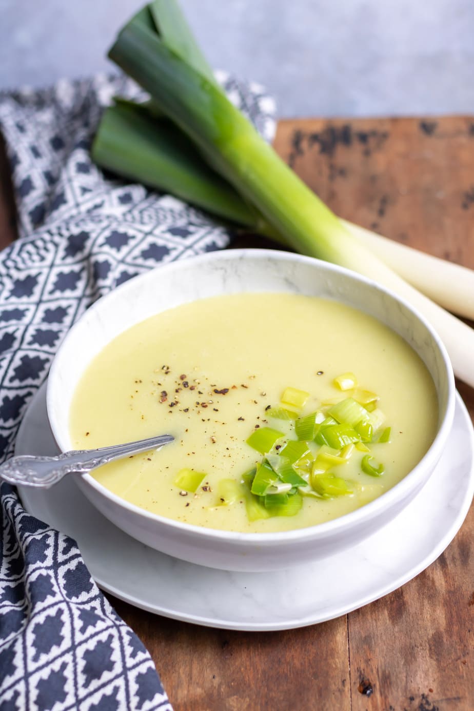 Spoon in a bowl of soup on a wooden table.