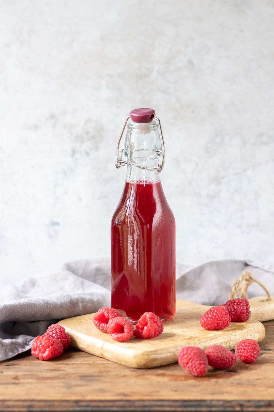Bottle of syrup next to raspberries.