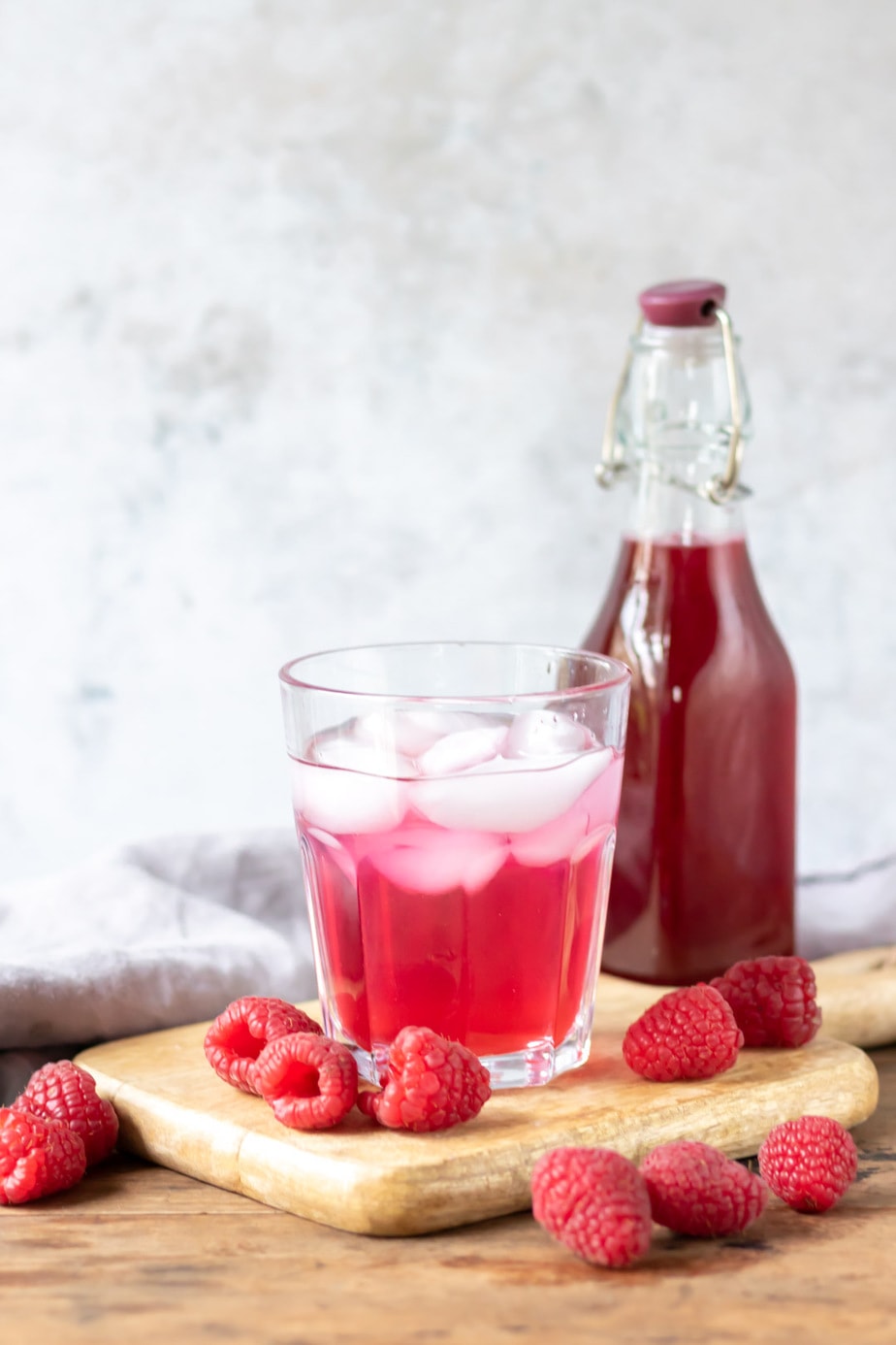 Glass of drink and bottle of raspberry syrup.