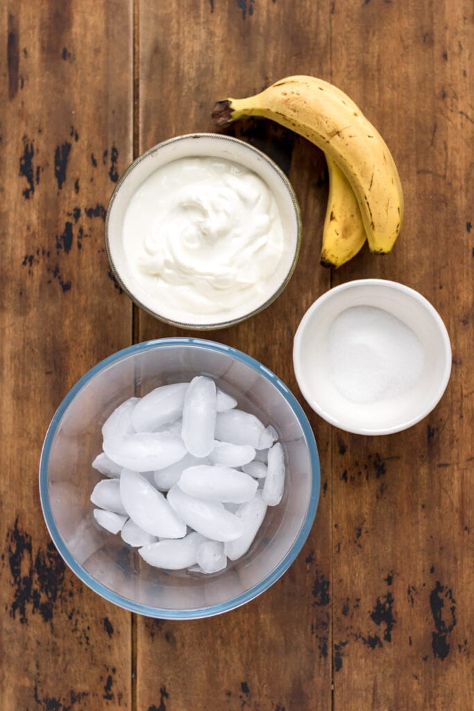 Table with ice, yogurt, sugar and ripe bananas.