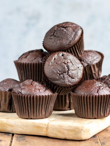 Pile of chocolate beetroot muffins on a board.