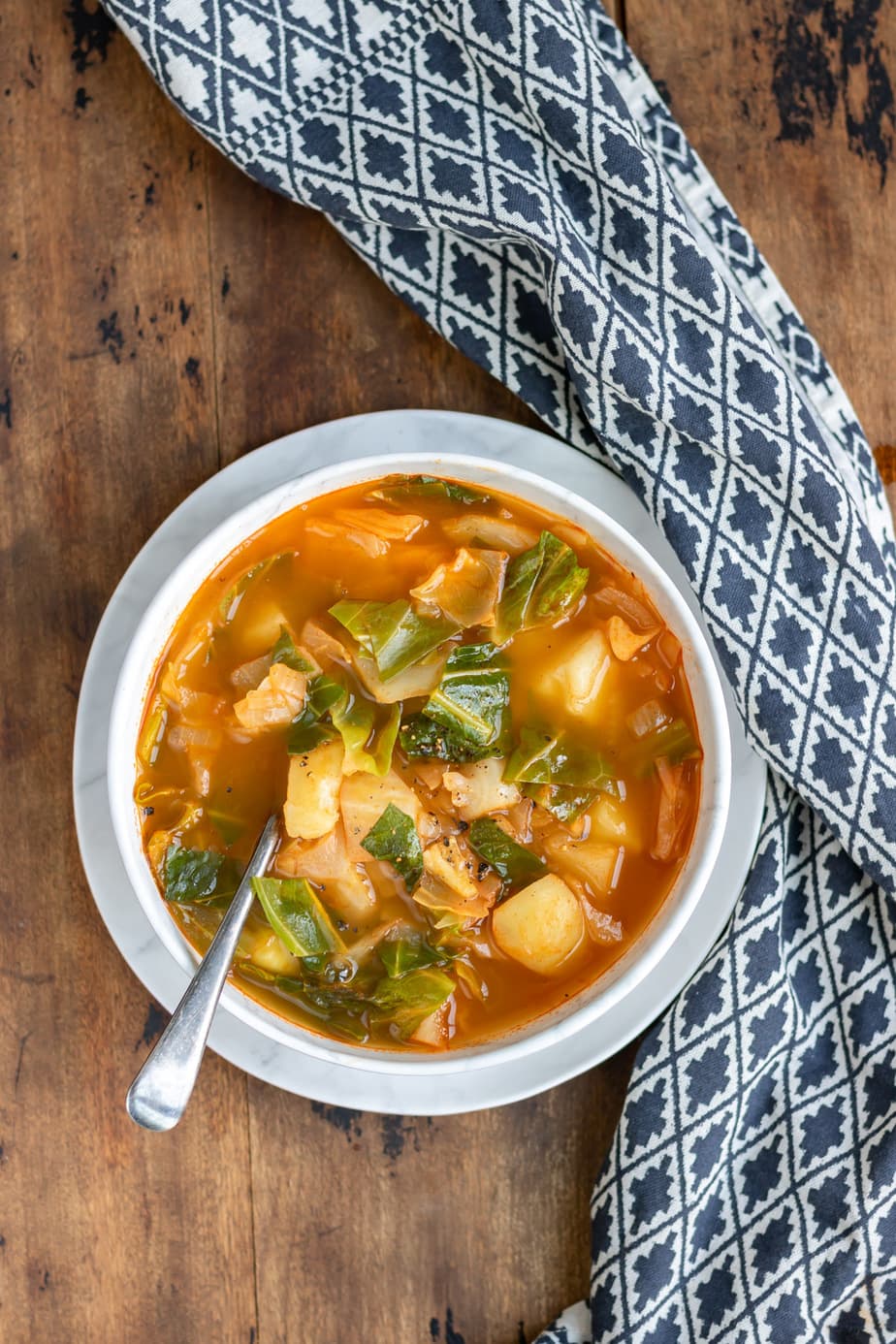 Bowl of cabbage soup on a wooden table.