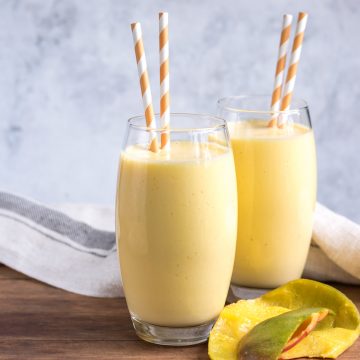 Two glasses of mango shake with striped straws.
