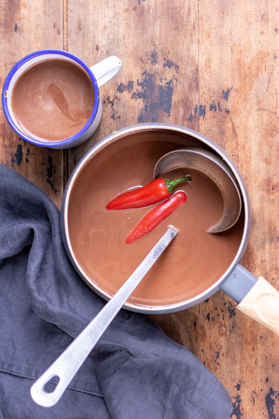 Pot of hot chocolate with chili pepper in it and a ladle in the pot.