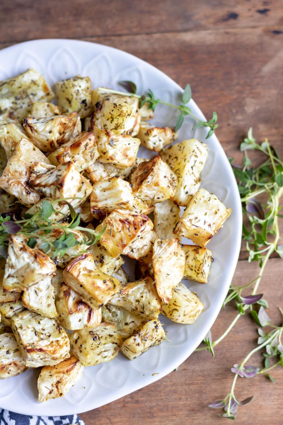 Bowl of cooked celeriac topped with herbs.