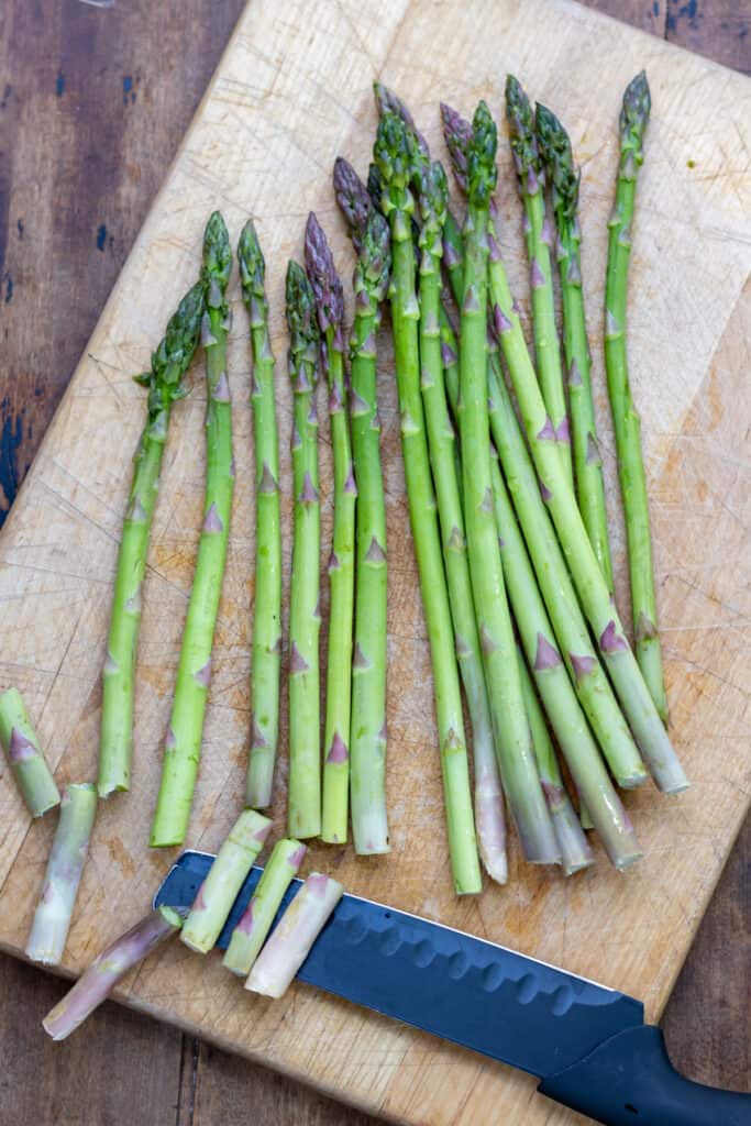 Trimming asparagus on a wooden cutting board.