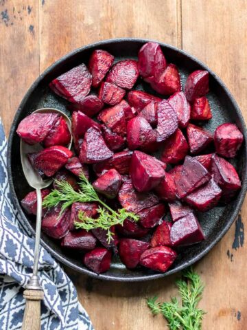 Serving dish of beets on a wooden table.