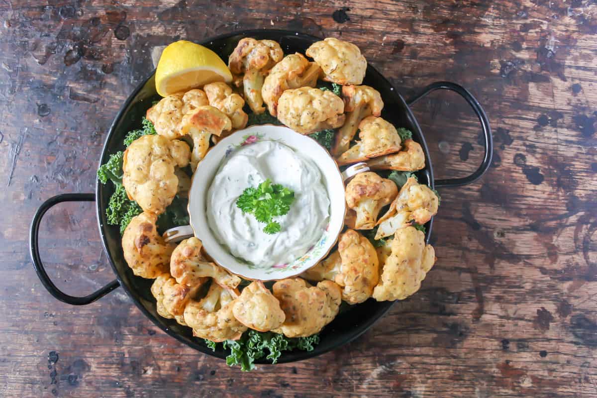 Serving dish of cauliflower wings with a bowl of dip.