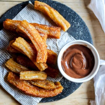 Looking down at a plate of churros and chocolate dipping sauce.