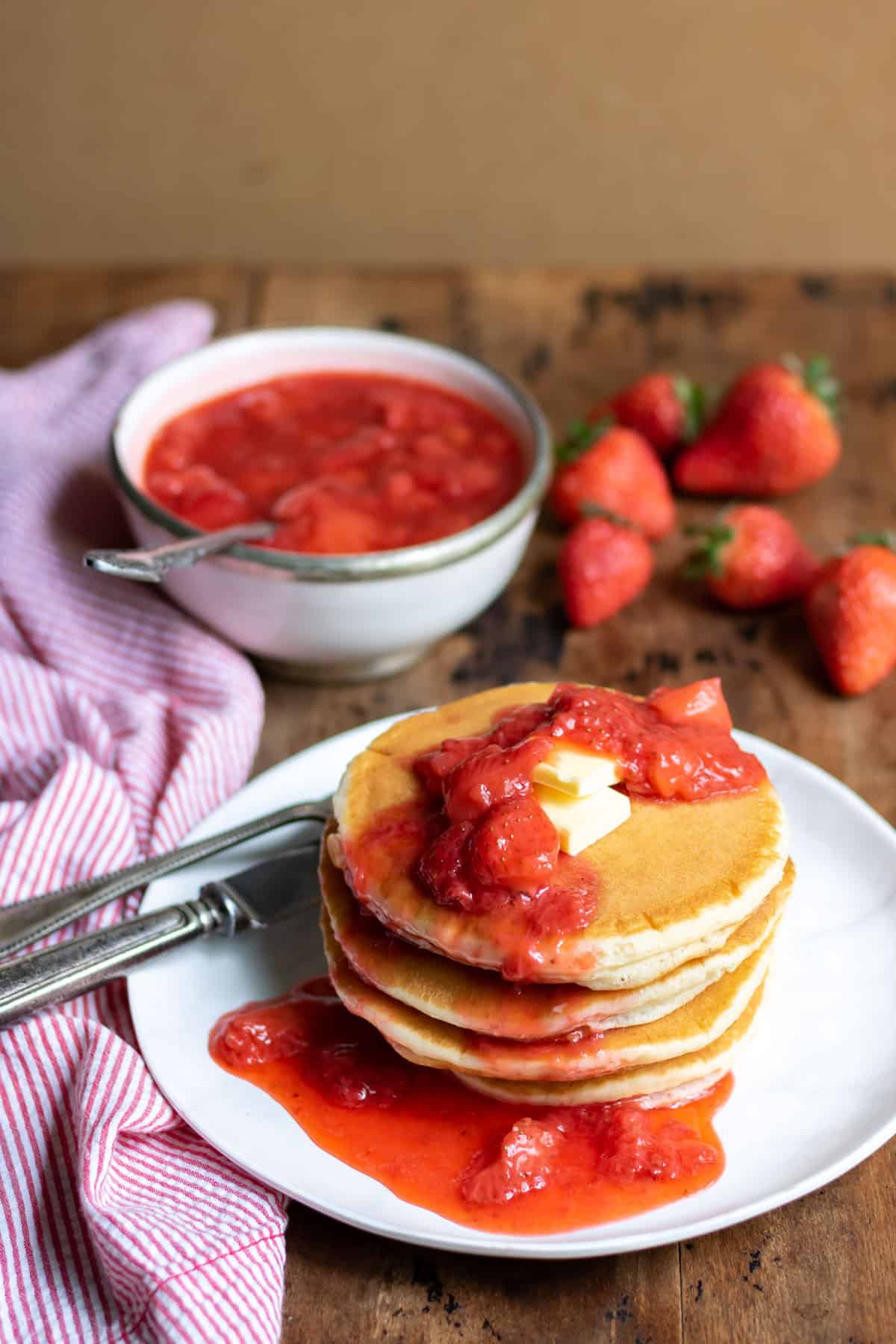 Stack of pancakes with butter and strawberry compote.