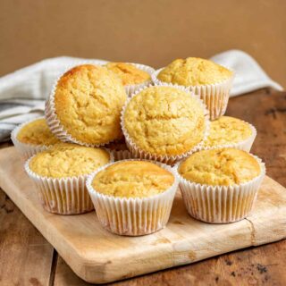 Pile of muffins on a board on a wooden table.