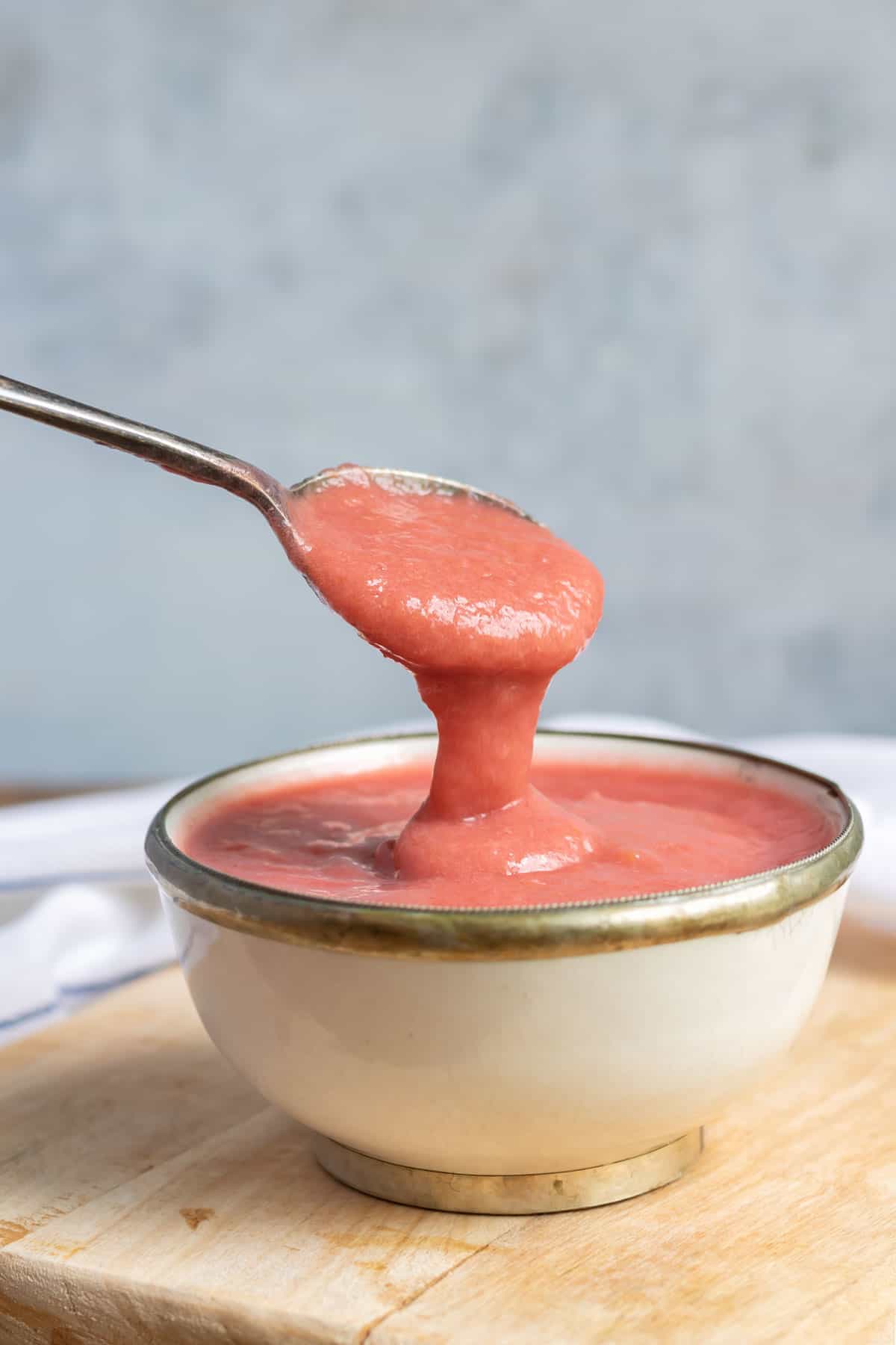 Spoonful of sauce coming out of a bowl.