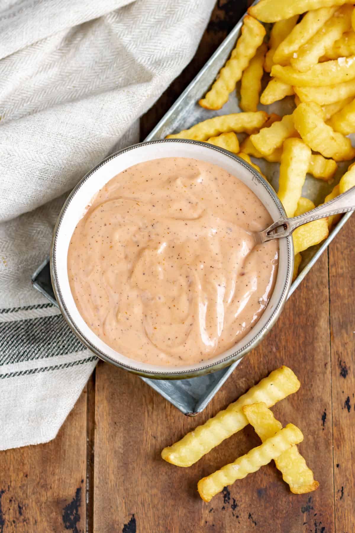 Table with a bowl of zax sauce and fries.