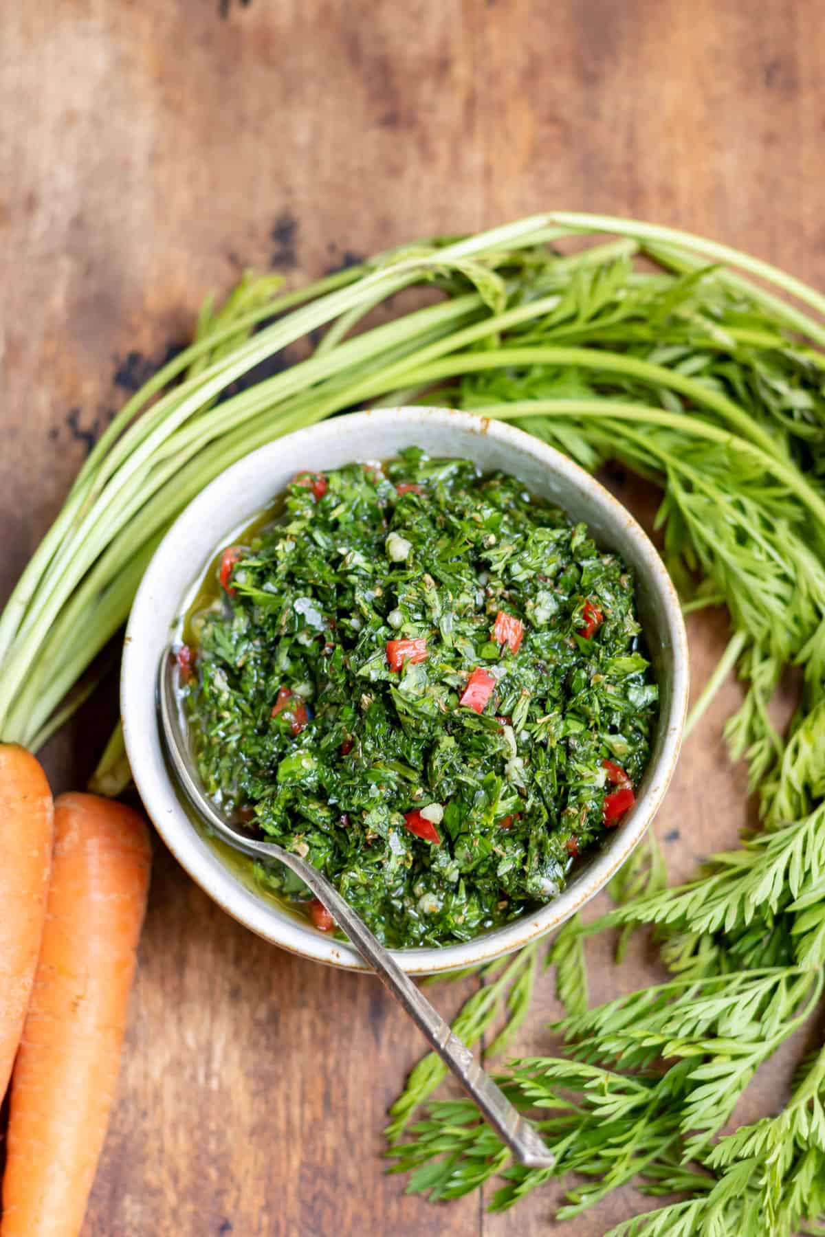 Bunched carrots around a bowl of chimichurri.