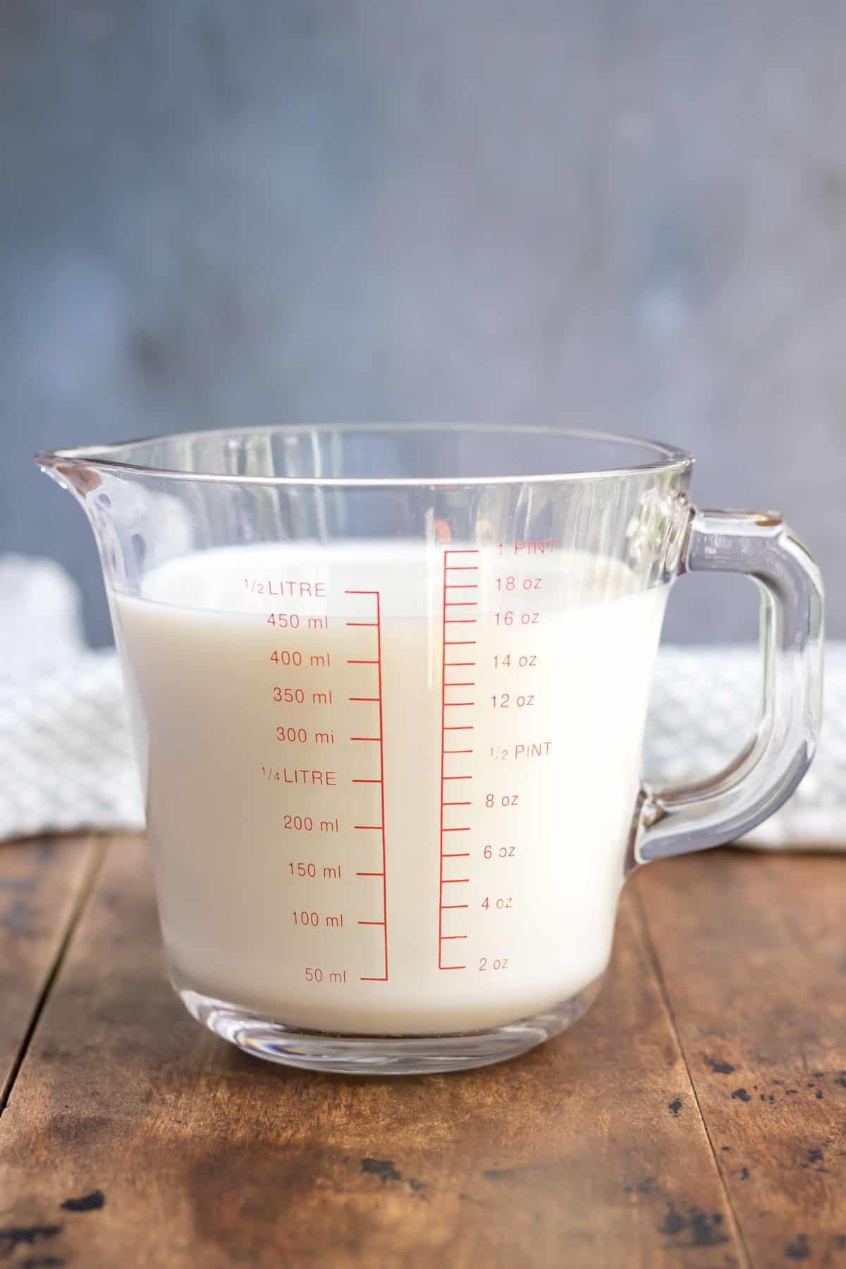 Measuring jug of milk on a wooden table.