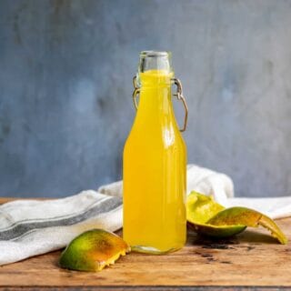 Table with bottle of syrup and mango peelings.