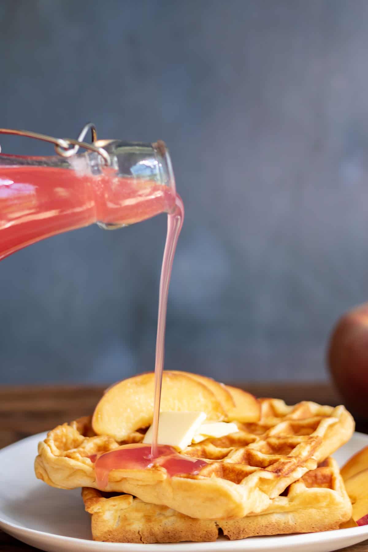 Peach syrup being drizzled onto waffles.