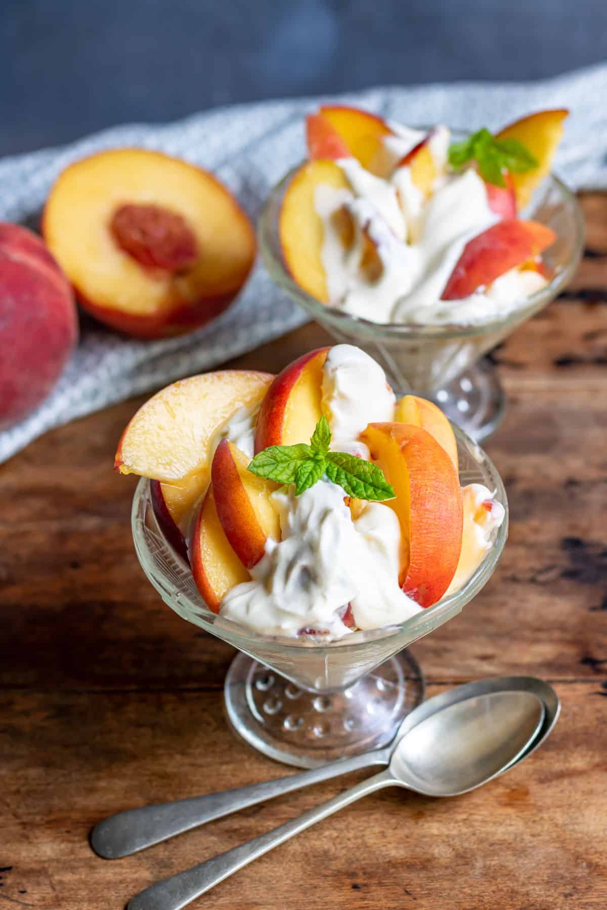 Glass dishes with peaches drizzled in a vanilla cream.