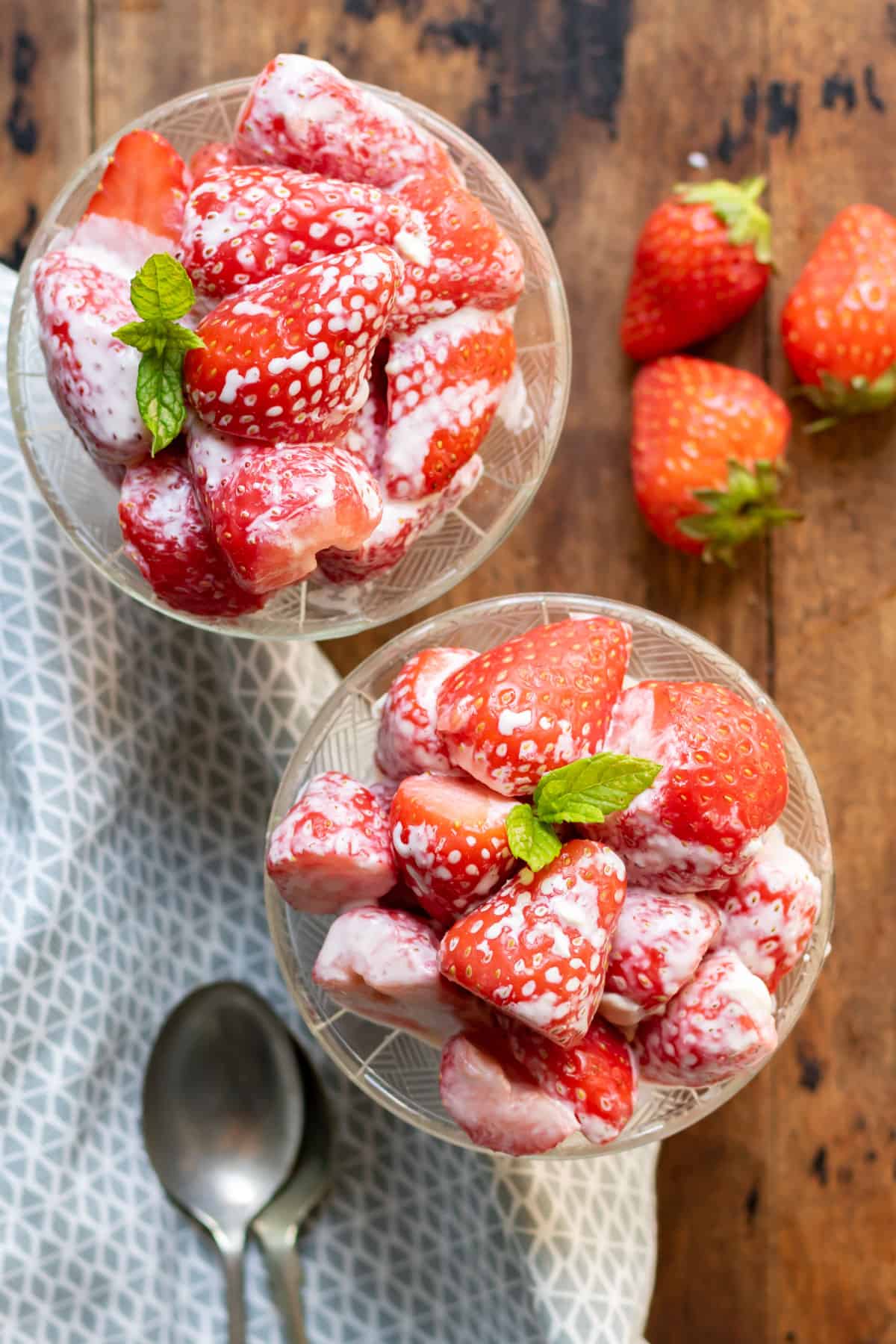 Two glass dishes with strawberries and cream.