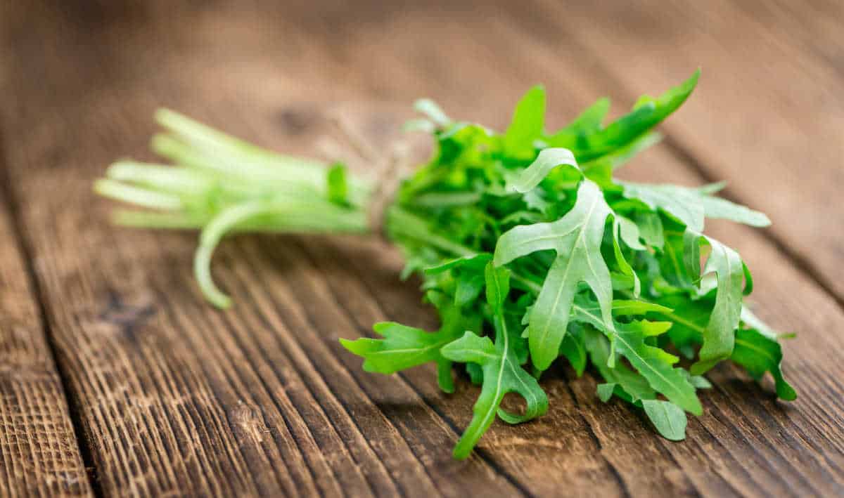 Bunch of arugula on a wooden table.