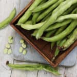 Broad beans on a tray and table.