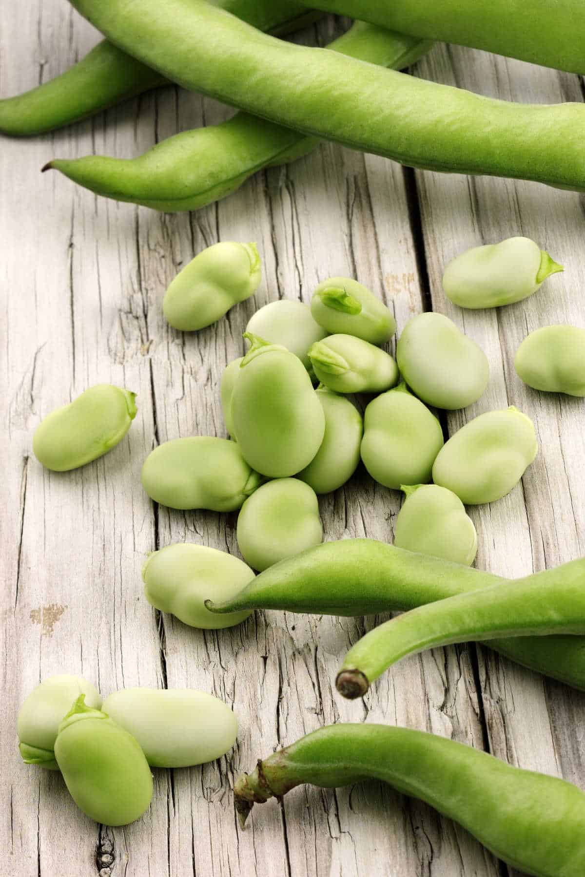 Wooden table with pods and broad beans.