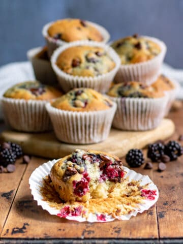 A pile of muffins with one in front with a bite out.