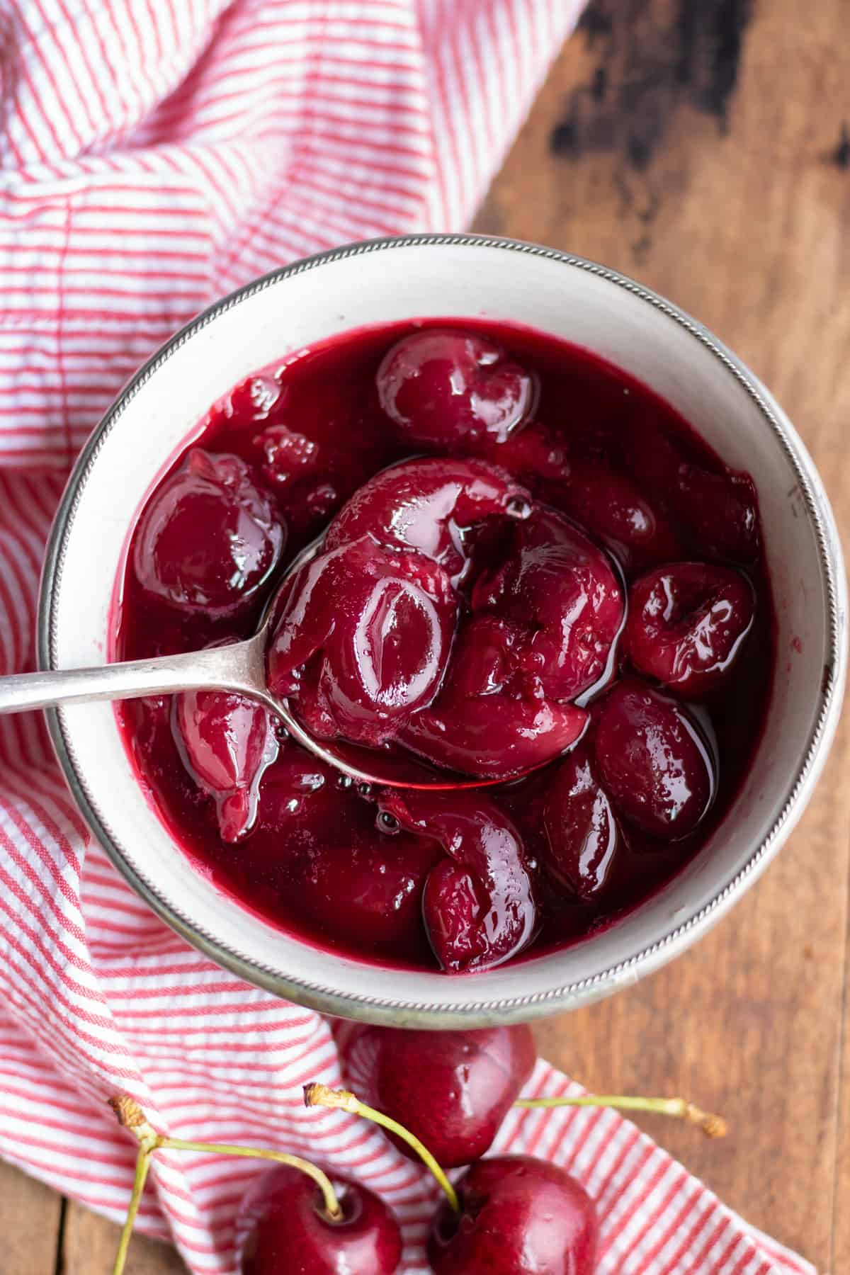 Dish of cherry compote with a spoon.