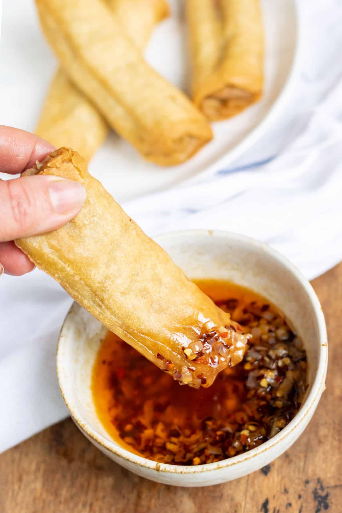 Spring roll in a bowl of dipping sauce.