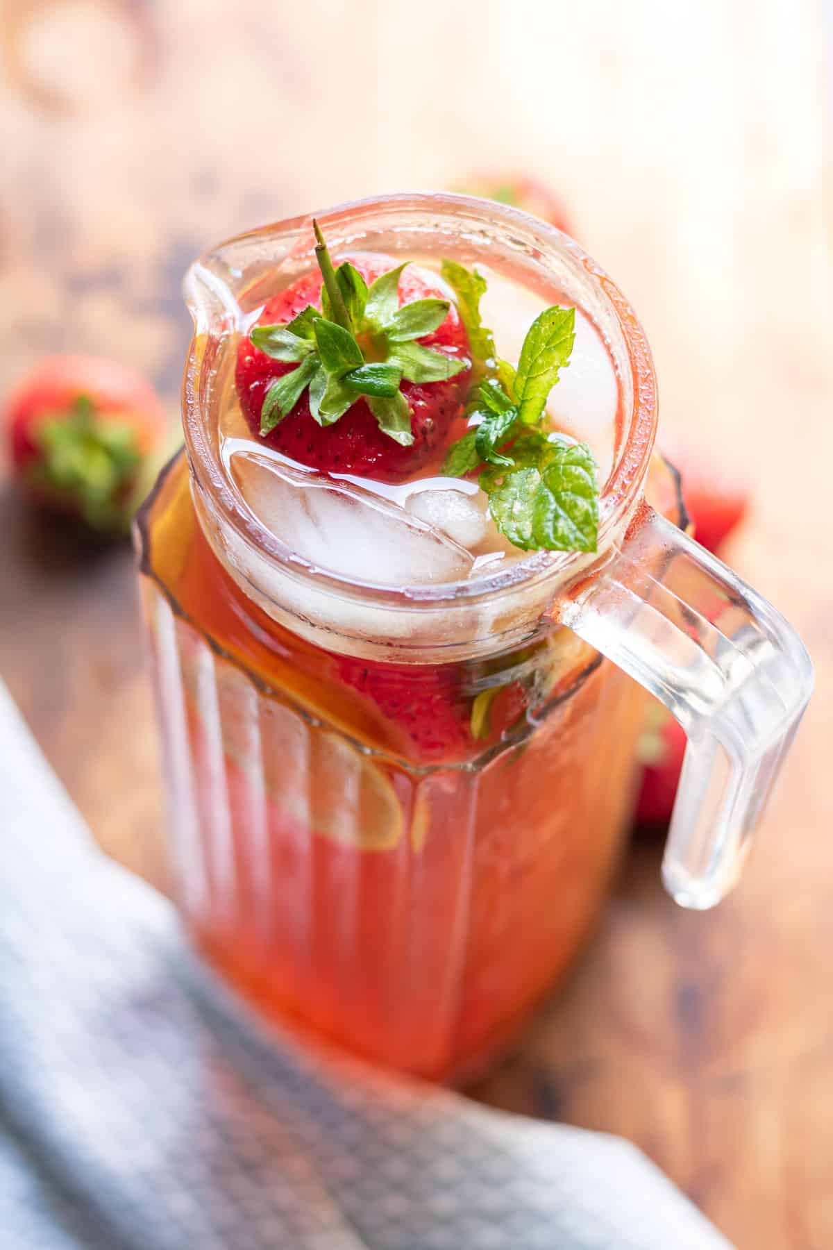 Pitcher of iced tea with strawberries.