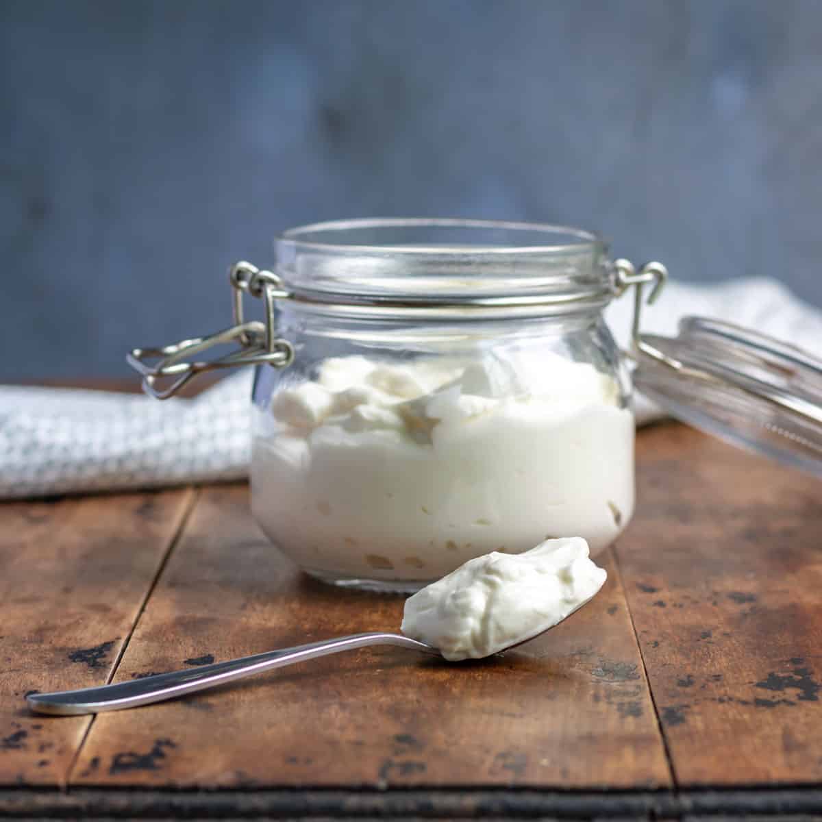 Jar of vegan mayo with a spoonful on the table.