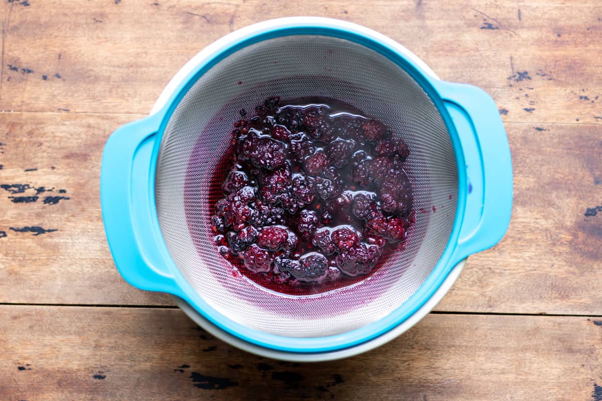 Straining blackberries out of the simple syrup.