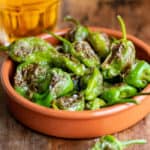 Terracotta dish of blistered padron peppers.