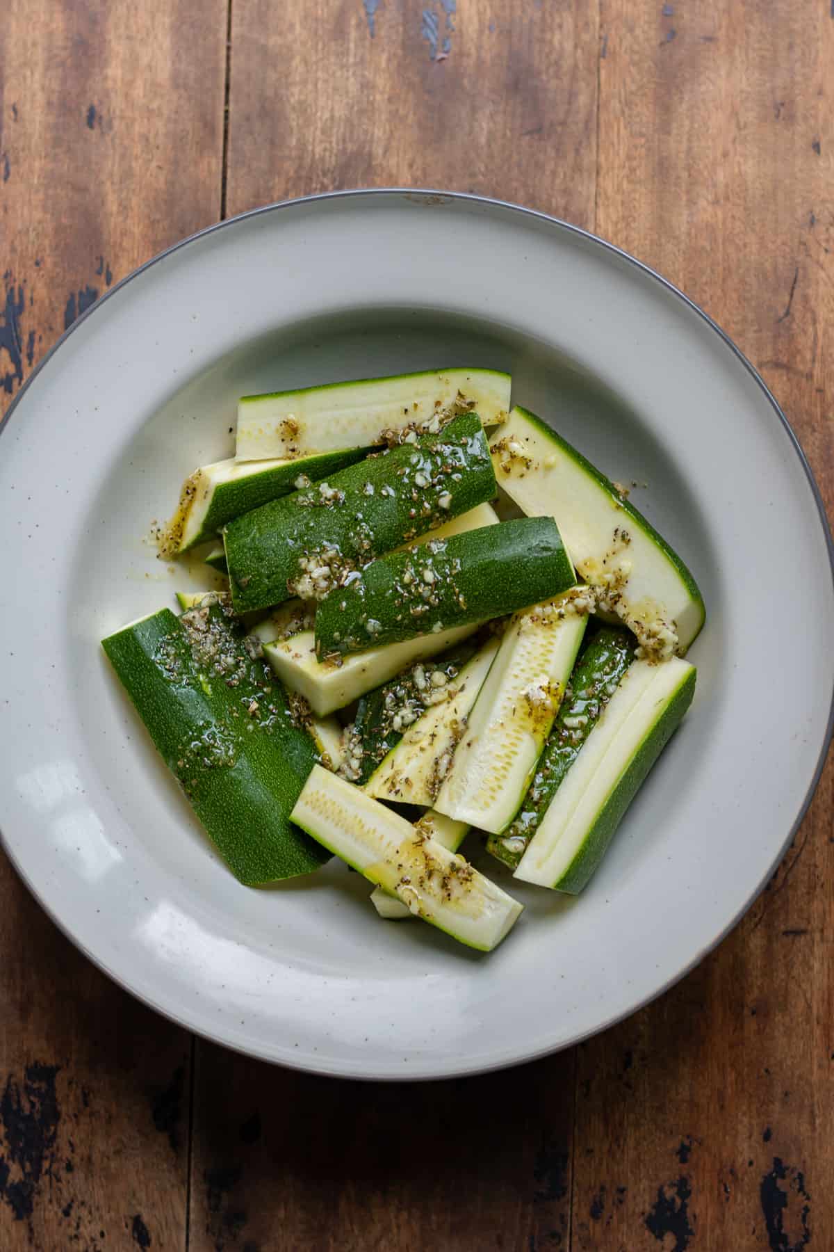 Spears of zucchini in a bowl with seasoning.