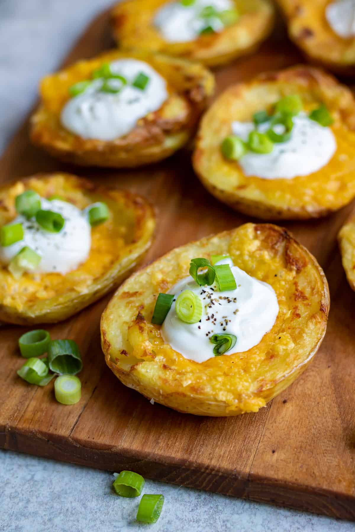 Close up of a potato skin topped with cheese and sour cream.